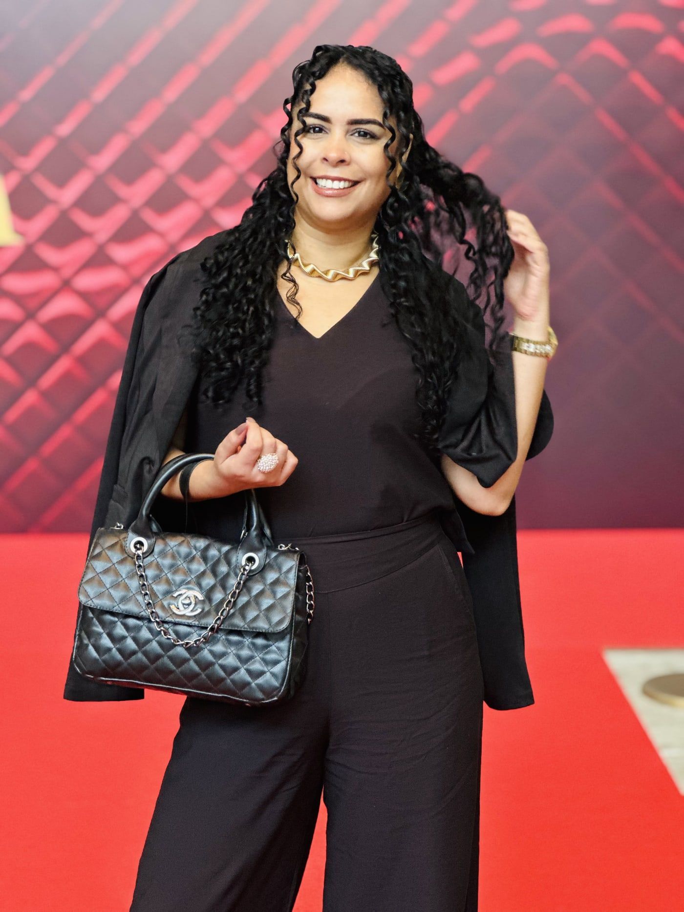 Bia Sampaio em evento, de preto, com bolsa